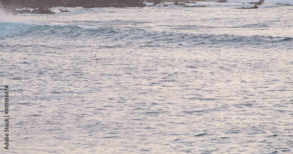 Panning up reveal at magic hour as pacific ocean waves crash against coast rocks. Panning up reveal at magic hour as pacific ocean waves crash against coast rocks.