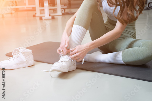 Fitness sport woman in fashion sportswear tying shoelaces on white sports shoes before exercise in the gym. 