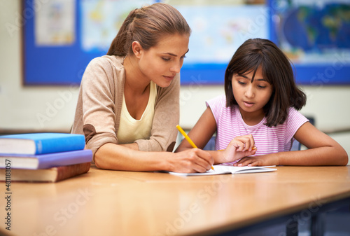 She's a dedicated educator. Shot of a teacher helping her student with her work in the classroom. photo