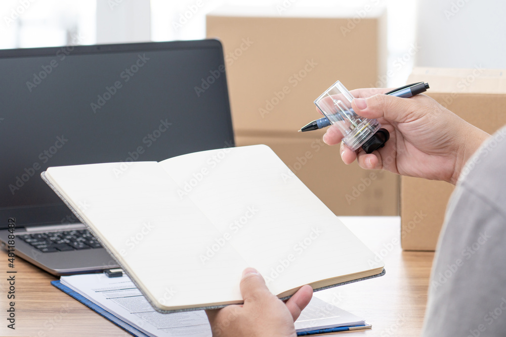 Fototapeta premium Close up hand a man hold car headlight bulb halogen and bulb case and hold note book with laptop on wood table in car service office : car part check and service concept