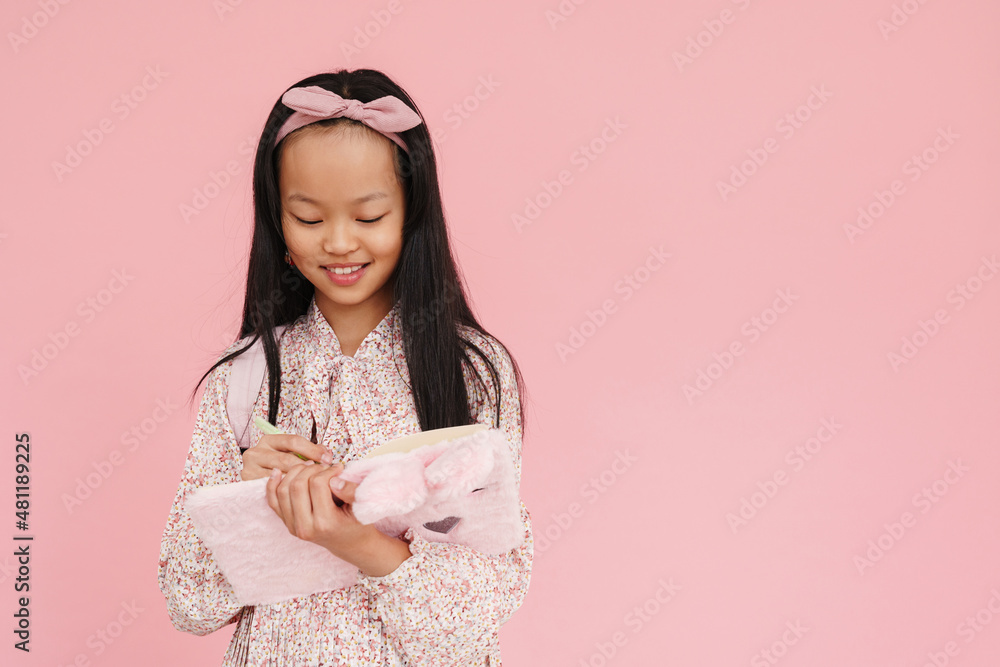 Asian girl wearing dress smiling while writing down notes Asian girl wearing dress smiling while writing down notes