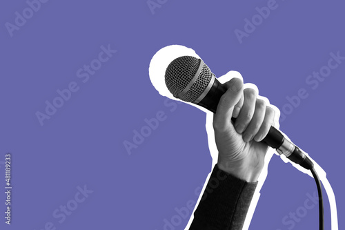 Female hand holding a microphone isolated on lilac Very Peri background