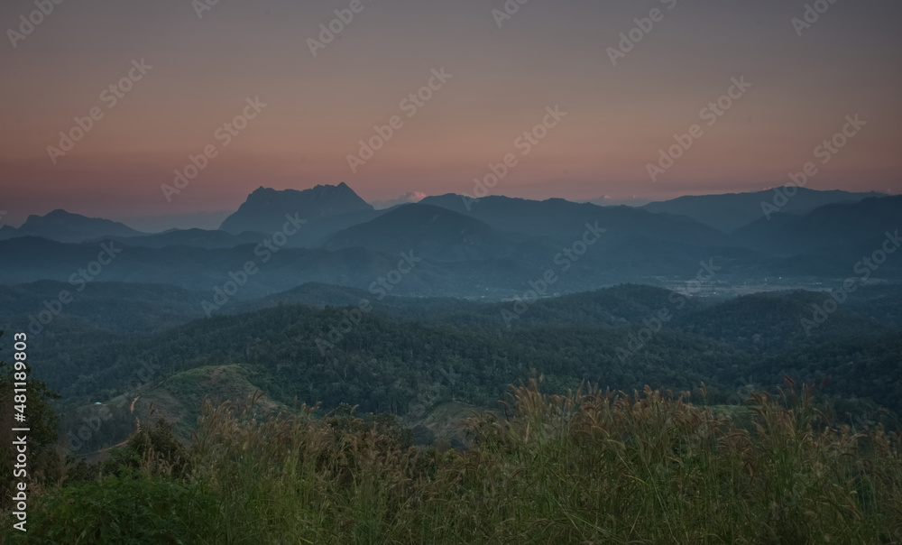 Obraz premium Mountain ridge, mountain range and village with faint fog in an evening