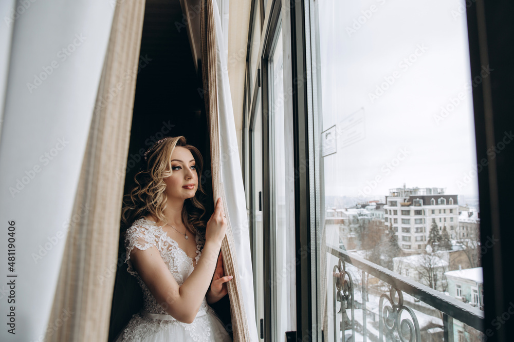 Bride in a white dress at the window. Bride morning. Getting ready for the upcoming wedding.