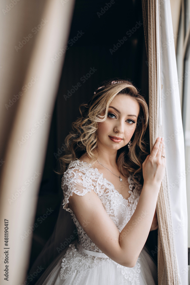 Fototapeta premium Bride in a white dress at the window. Bride morning. Getting ready for the upcoming wedding.