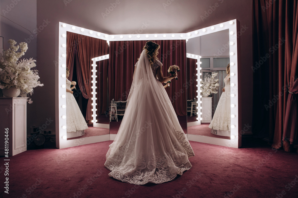 The bride in a white dress holds a beautiful wedding bouquet. Significant day. Burgundy background. The bride in a white dress holds a beautiful wedding bouquet. Significant day. Burgundy background.