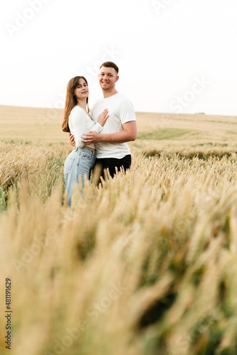 a couple in love stands among a wheat field and hold hands. a guy and a girl are walking in nature. vacation outside the city