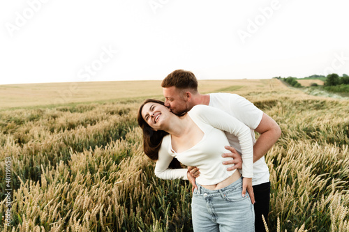 young guy with a girl are walking on a beautiful sunset of the day. couple in wheat field © Vadym