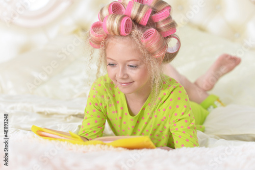 Lovely little girl with pink curlers reading