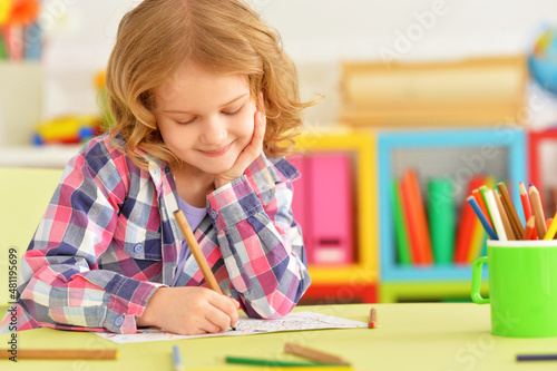 Portrait of cute smiling girl posing and drawing at home