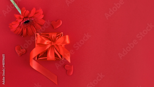 gift box with ribbon, gerbera flower, heart on red background. valentines day concept. greeting card. copy space, place for text, banner