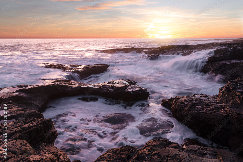 Beautiful sunrise at the coast with amazing vibrant colours and long exposure of the crashing waves 