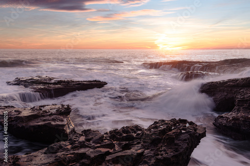 Beautiful sunrise at the coast with amazing vibrant colours and long exposure of the crashing waves  © Joe