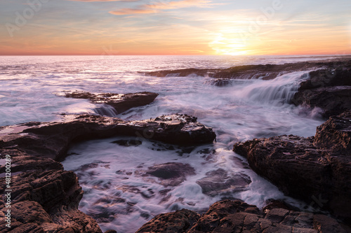 Beautiful sunrise at the coast with amazing vibrant colours and long exposure of the crashing waves 