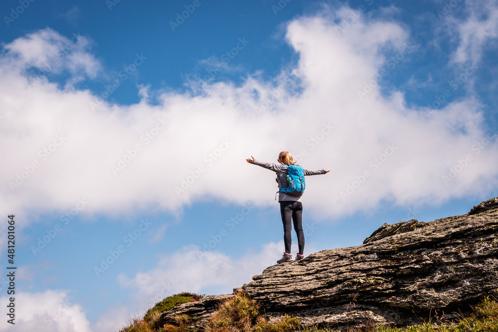 Vacation at mountains. Hiker standing at mountain peak with arms outstretched. Woman feeling connection with nature Vacation at mountains. Hiker standing at mountain peak with arms outstretched. Woman feeling connection with nature