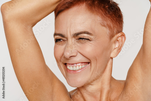 Senior shirtless woman with short hair smiling and winking