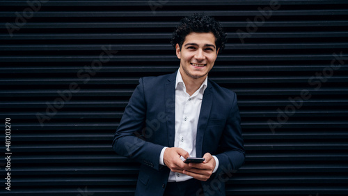 A man in an official suit holds a phone in his hands, writes a social network message