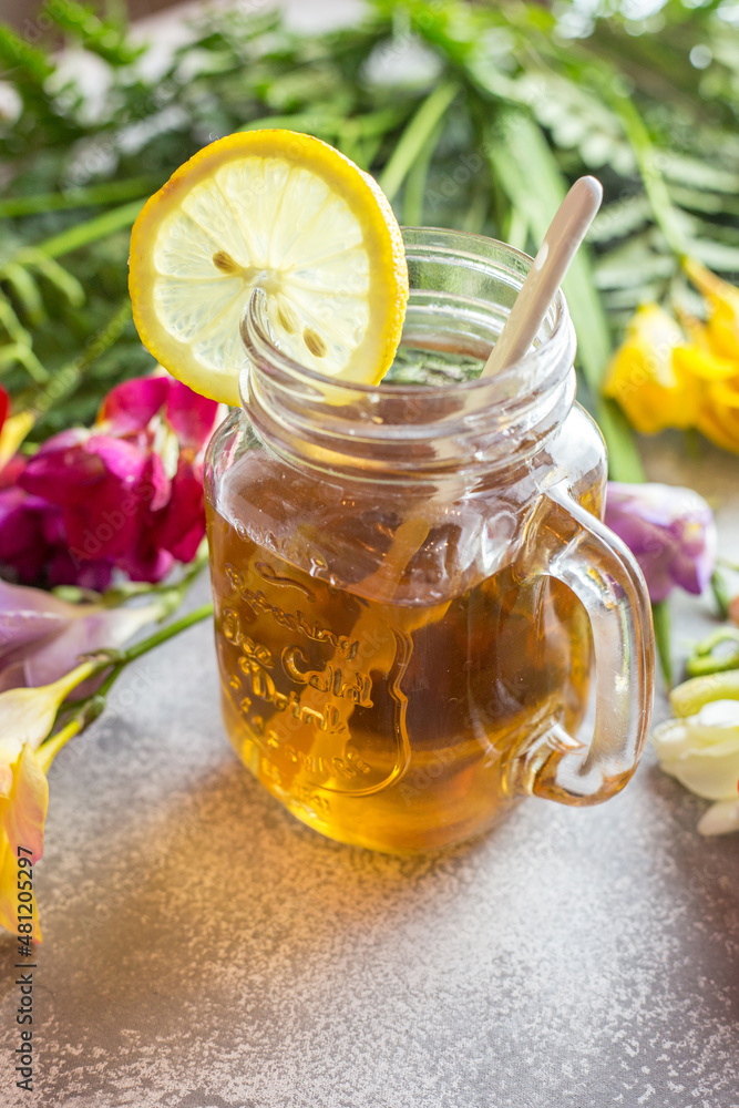 Delicious honey in glass jar with lemon arranged on table with flowers Delicious honey in glass jar with lemon arranged on table with flowers