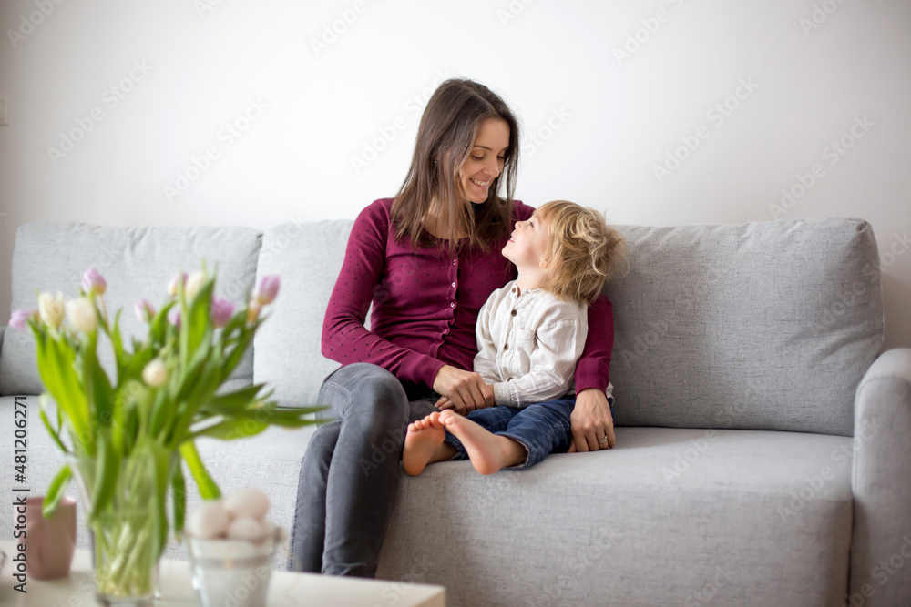 Beautiful blond boy, giving mother flowers and box with little gift for mothers day Beautiful blond boy, giving mother flowers and box with little gift for mothers day