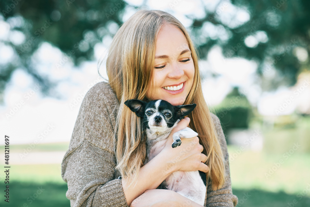Outdoor portrait of happy young woman hugging small chihuahua black and white dog Outdoor portrait of happy young woman hugging small chihuahua black and white dog
