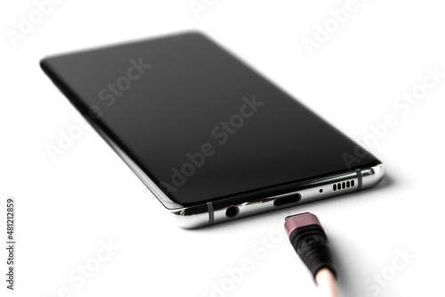 Smartphone and a charger on white background photo