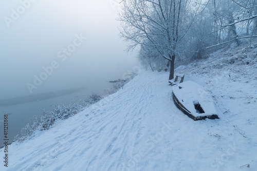 Snow covered path next to Tisza river in Hungary on a foggy morning