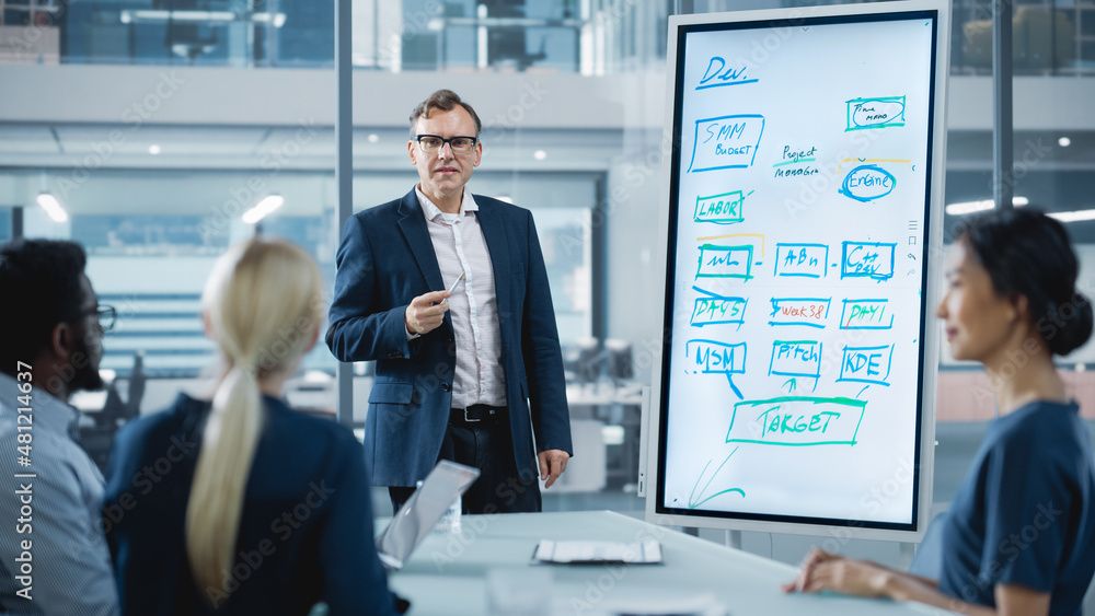 Company Operations Manager Holds Meeting Presentation for a Team of Economists. Adult Male Uses Digital Whiteboard with Company Project Management Plan, Charts, Data. People Work in Business Office. Company Operations Manager Holds Meeting Presentation for a Team of Economists. Adult Male Uses Digital Whiteboard with Company Project Management Plan, Charts, Data. People Work in Business Office.