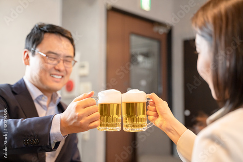 飲食店にてビールで乾杯をする男女
