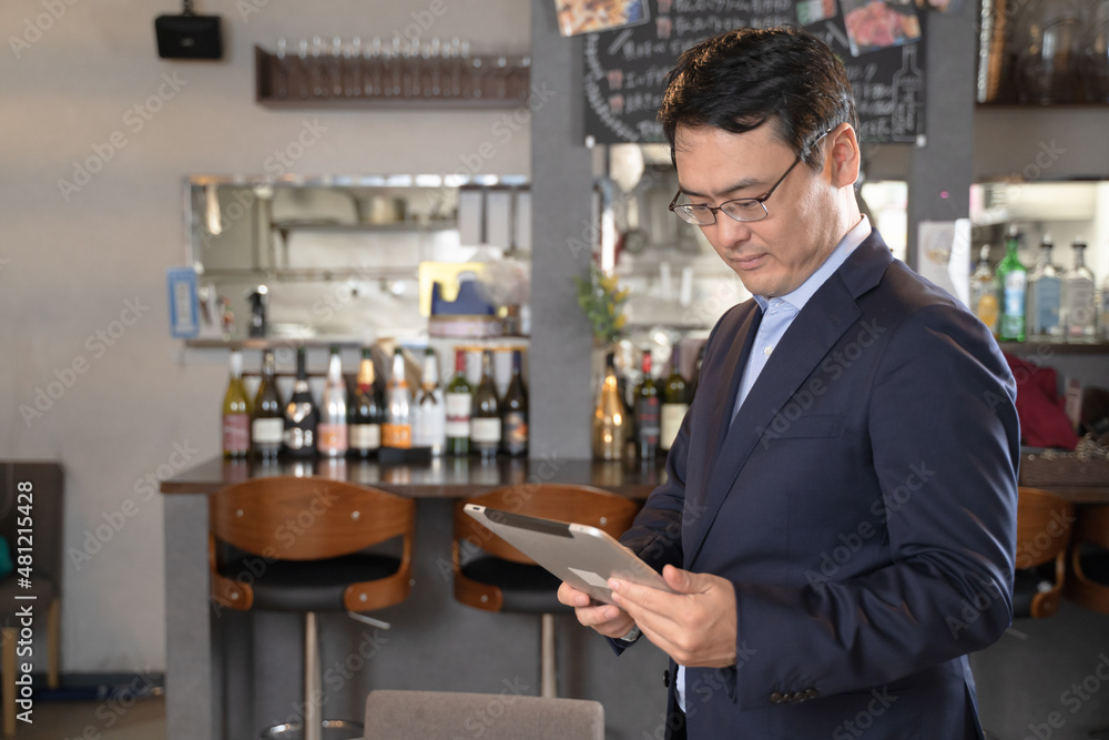 タブレットを持ってレストランを経営する男性 タブレットを持ってレストランを経営する男性