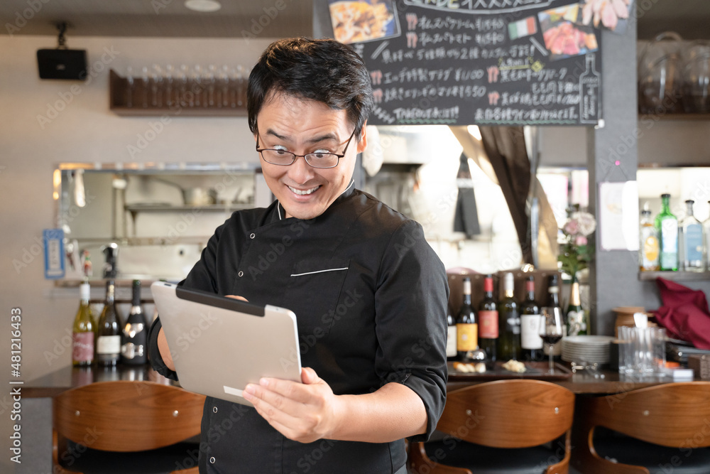飲食店でタブレットを操作する男性スタッフ 飲食店でタブレットを操作する男性スタッフ
