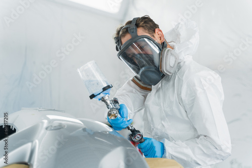 Male car painter during painting vehicle body elements