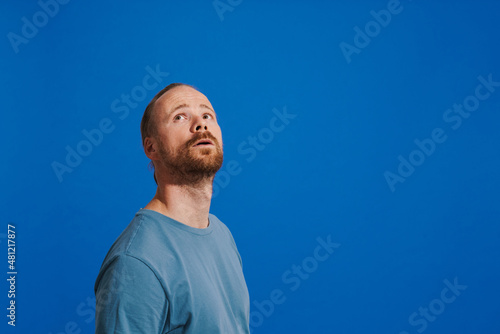 Ginger puzzled man with beard posing and looking upward