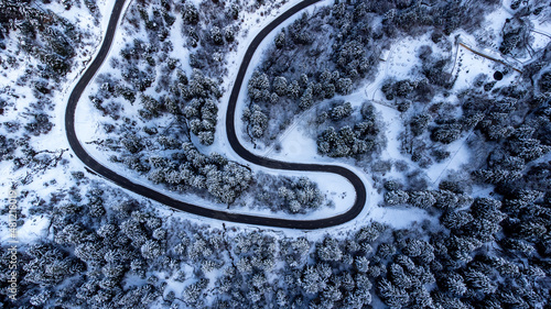 Aerial view of the road between the pines. Snowy winter landscape. drone photography