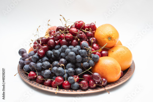 Ripe fruits on a copper tray oranges, cherries, grapes