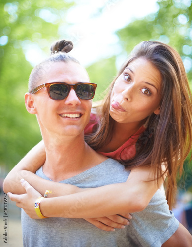 Care-free couple. A trendy young man giving his female friend a piggyback ride.