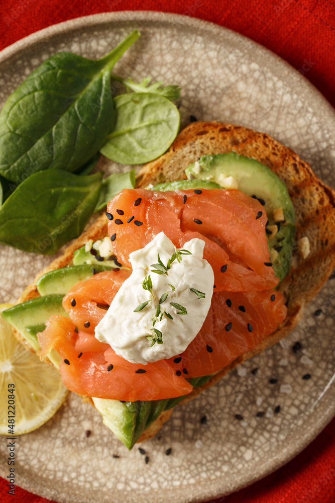 Toast with salmon, cream cheese, avocado, fresh salad on plate Toast with salmon, cream cheese, avocado, fresh salad on plate