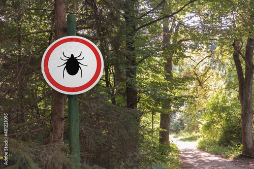 Warning sign beware of ticks in infested area in the forest.