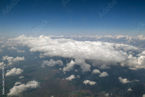Aerial view from airplane window of white puffy clouds on bright sunny day
