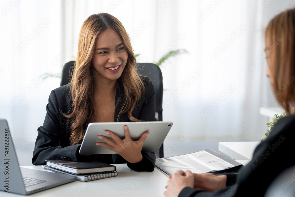 Fototapeta premium Two beautiful Asian businesswoman talking exchange ideas at work.