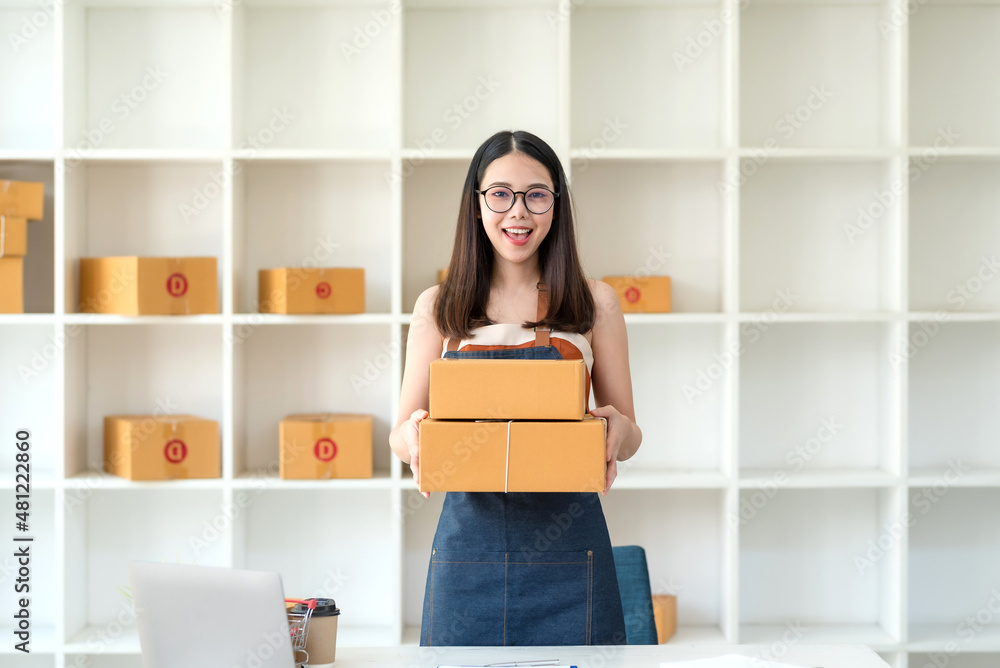 Portrait of young Asian female business owner wearing an apron sell products online looking at camera Portrait of young Asian female business owner wearing an apron sell products online looking at camera