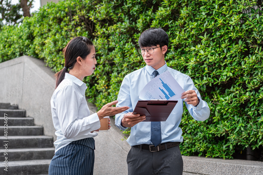 Young business woman holding coffee cup to talking with business man about investment chart report Young business woman holding coffee cup to talking with business man about investment chart report