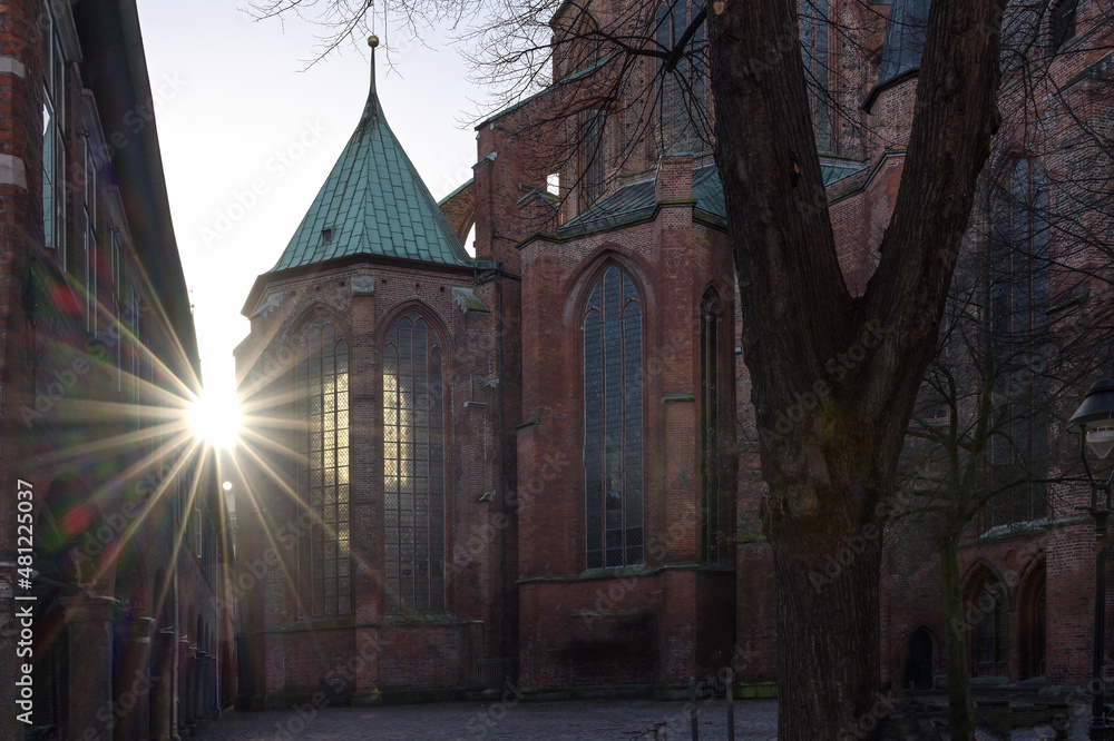 Sun star with lens flares at the historic Marienkirche (St. Mary's church) of Lubeck in Germany, a famous basilica made of red bricks, landmark and tourist destination, copy space, selected focus