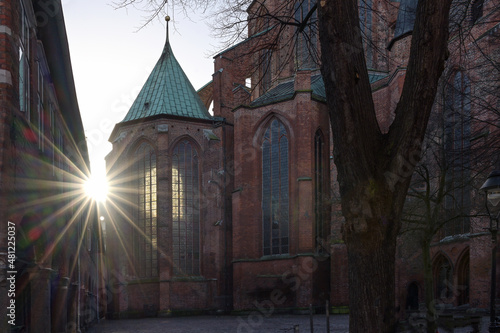 Sun star with lens flares at the historic Marienkirche (St. Mary's church) of Lubeck in Germany, a famous basilica made of red bricks, landmark and tourist destination, copy space, selected focus