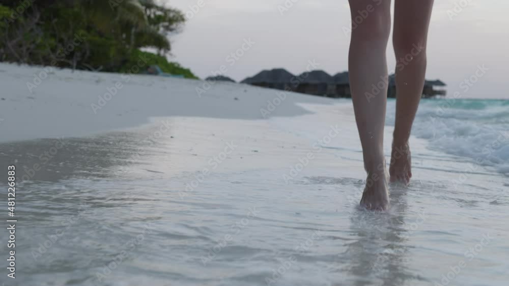 Slow motion of woman feet walking barefoot on the white sand beach at sunset. Female tourist on summer vacation in Maldives. Slow motion of woman feet walking barefoot on the white sand beach at sunset. Female tourist on summer vacation in Maldives.