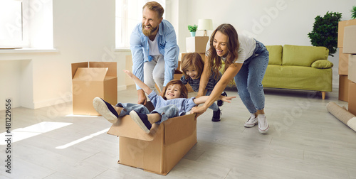 Happy excited young family having fun in spacious interior of new home. First-time buyers playing with boxes and laughing. Real estate, residential mortgage, buying house concept. Banner background