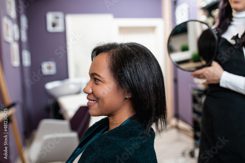 An middle aged African American woman on a curly hair straightening treatment at a hair salon. photo