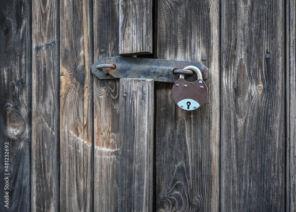 A simple padlock on an old, weathered, wooden door. A simple padlock on an old, weathered, wooden door.