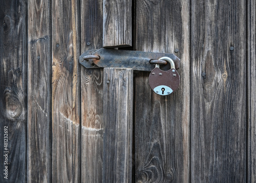 A simple padlock on an old, weathered, wooden door. © Bob