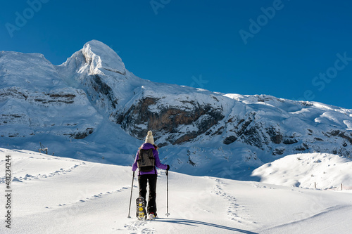 A young girl with snow rackets, walks through a completely snowy landscape in the Pyrenees mountain range (Spain)