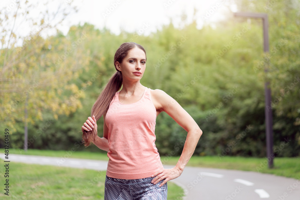 Beautiful athletic woman standing running track in summer park Portrait caucasian female jogger outdoor Beautiful athletic woman standing running track in summer park Portrait caucasian female jogger outdoor